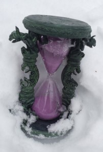 An hourglass filled with purple sand, rests in the snow