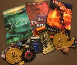 A stack of my published novels and several medals from races I've finished