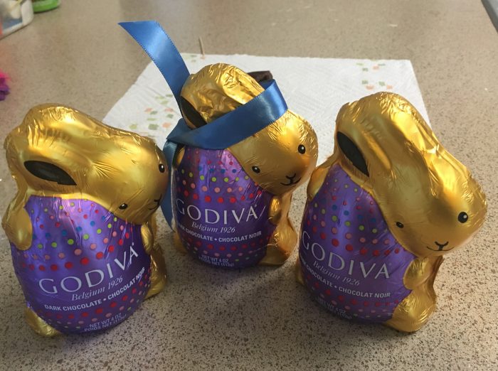 Three chocolate foil wrapped bunnies. The one in the center wears a bow to hide seam where the ears were stolen.